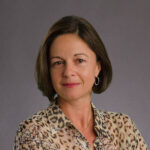 Fiona Murray headshot wearing leopard print blouse on grey background